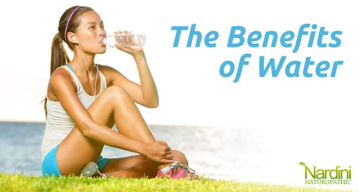The Benefits of Water & How To Prevent Dehydration | Woman sitting on the grass drinking a bottle of water | Dr. Pat Nardini | Toronto Naturopath